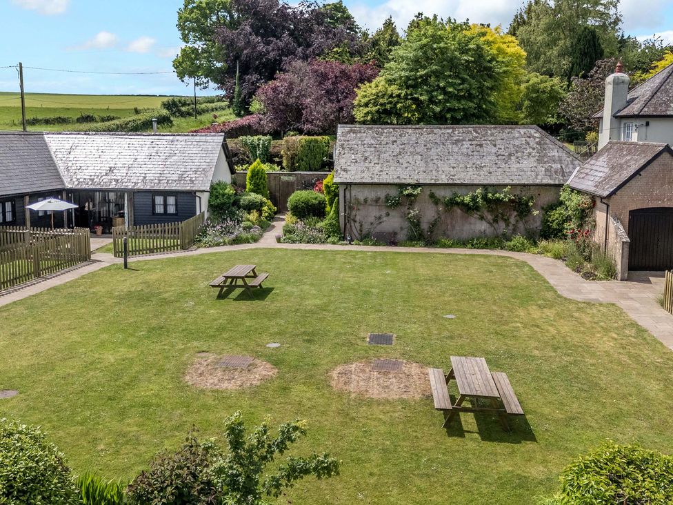 A garden with tables and buildings at Corner Barn in Winterborne Stickland