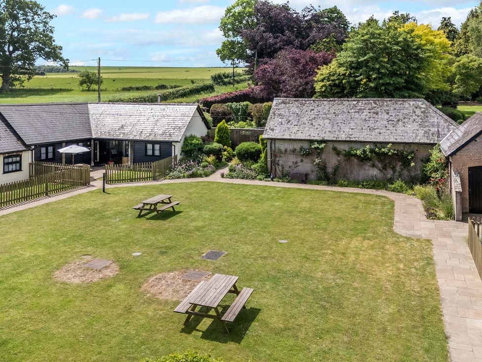 An outdoor area with a garden and tables at Corner Barn in Winterborne Stickland