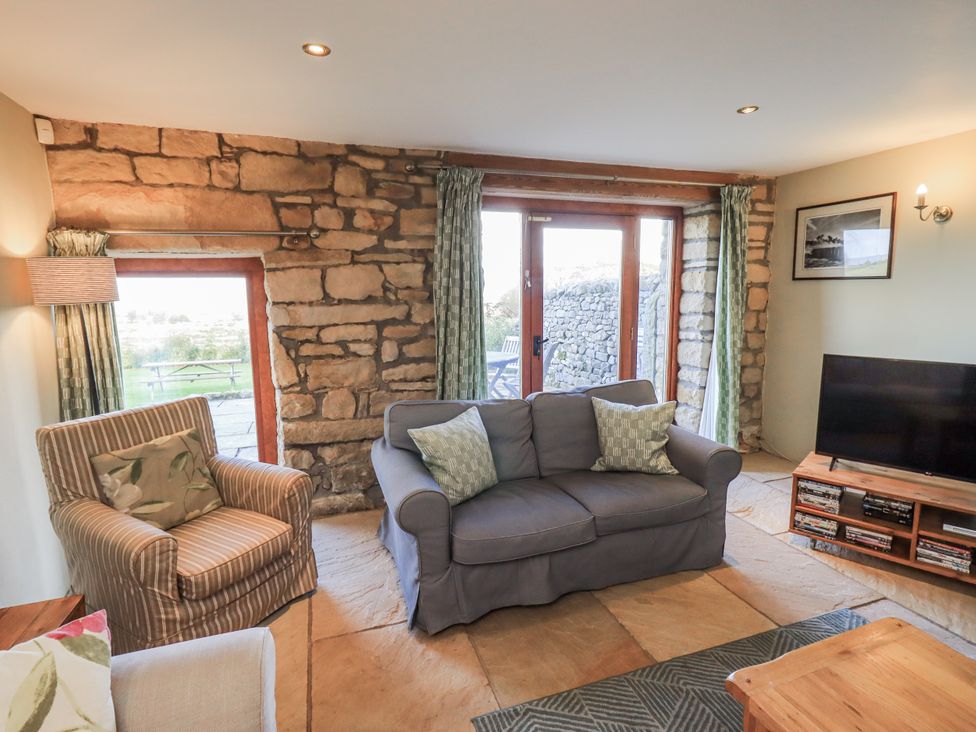 A living room with a sofa, armchair, and television at Usherwoods Dairy in Tatham