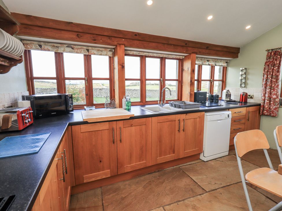 A kitchen with wooden cabinets, sink, and appliances at Usherwoods Dairy in Tatham