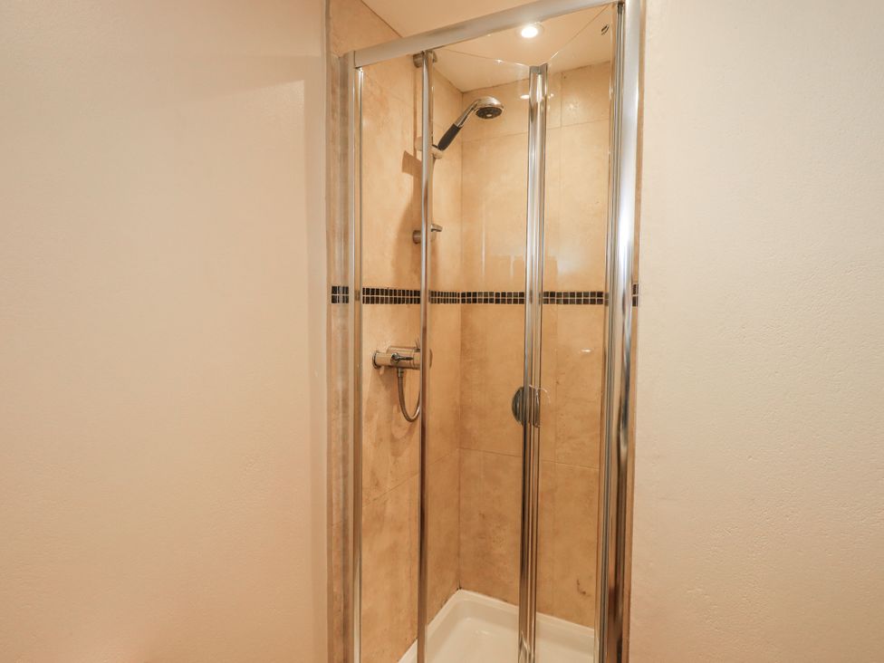 A shower enclosure with glass doors and wall tiles at Usherwoods Dairy in Tatham