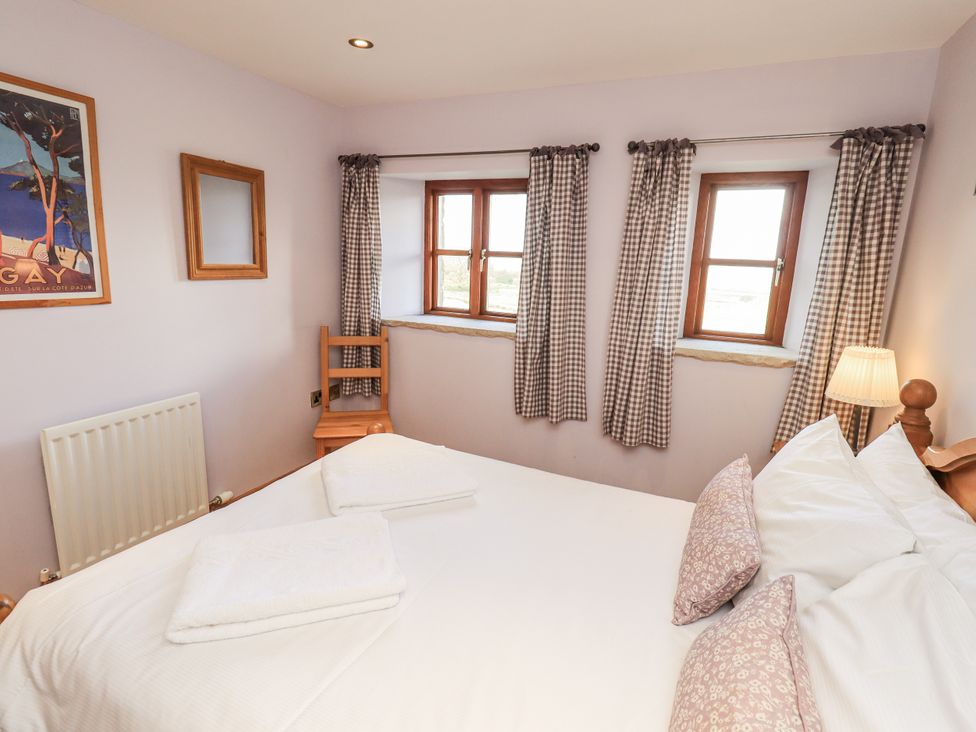 A bedroom with a bed, two windows, and a chair at Usherwoods Dairy in Tatham