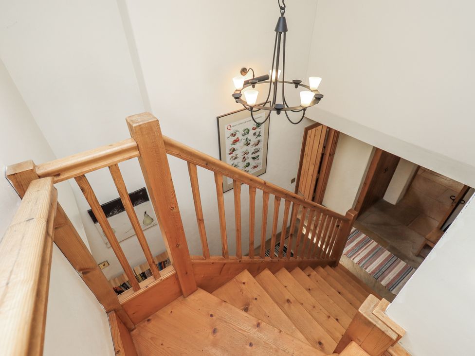 A staircase with wooden railing and chandelier at Usherwoods Dairy in Tatham