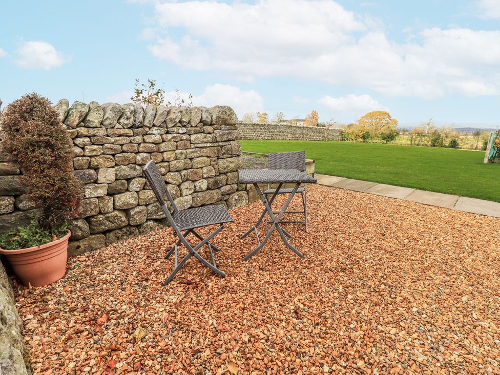 A garden with a stone wall, table and chairs at Usherwoods Dairy in Tatham