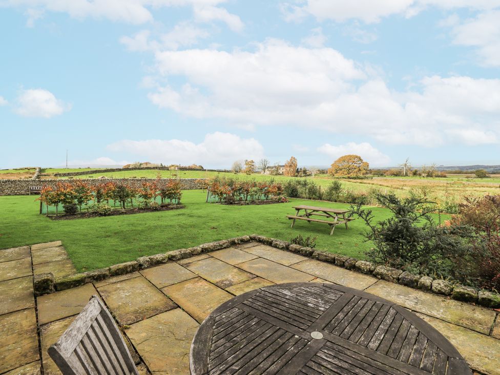 A garden with a stone patio, table, and seating at Usherwoods Dairy in Tatham