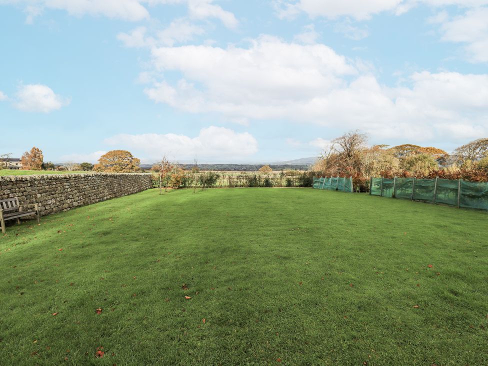 A garden with grass and a stone wall at Usherwoods Dairy in Tatham