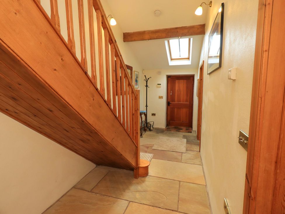 A hallway with a staircase and coat rack at Usherwoods Barn Tatham