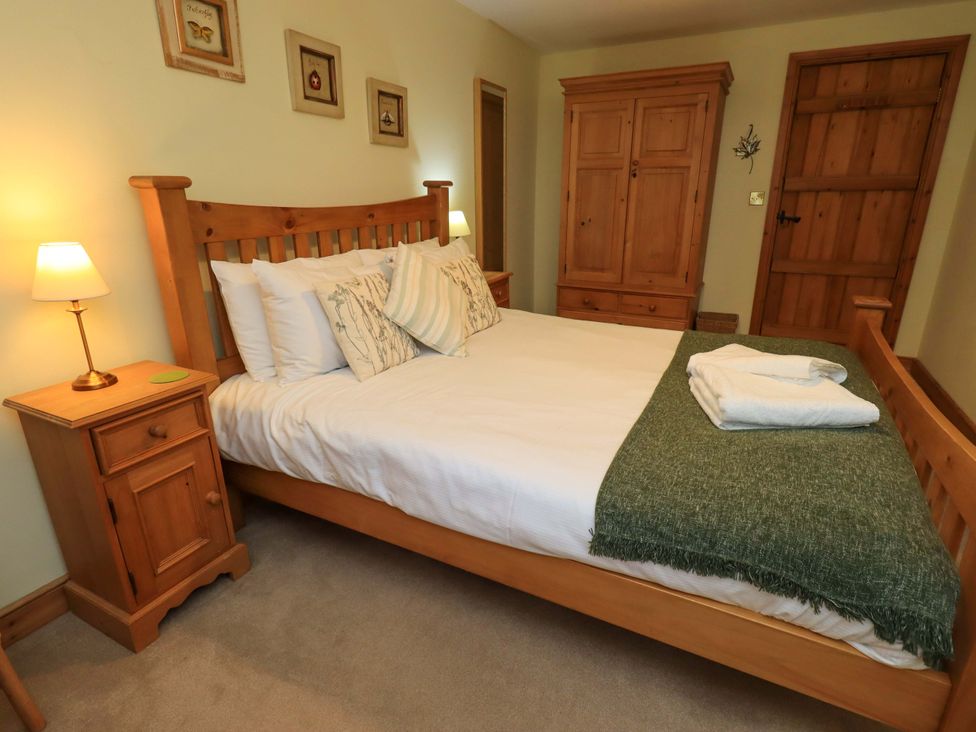 A bedroom with a wooden bed and nightstand at Usherwoods Barn in Tatham