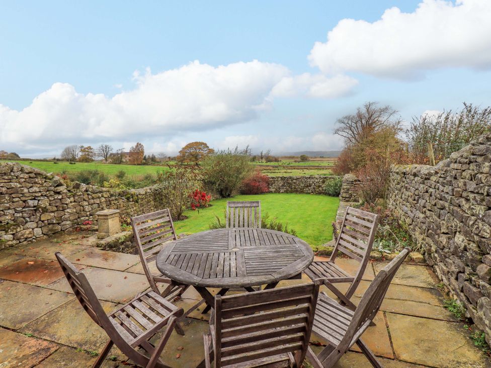 A garden with a wooden table and chairs at Usherwoods Barn in Tatham