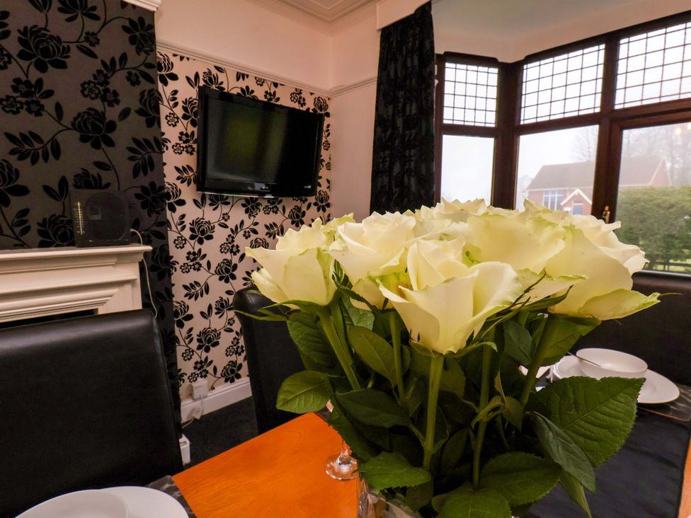 A dining room with a television and a vase of roses at Dilston House in Goathland
