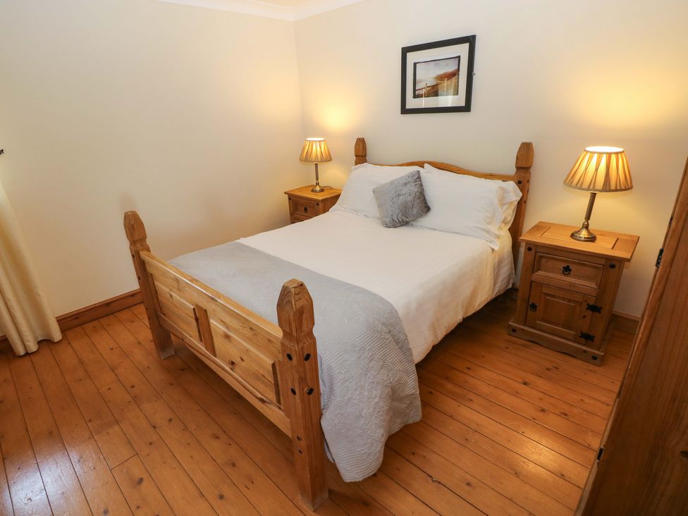 A bedroom with a bed and nightstands at The Dairy in Penuel near Llanmorlais