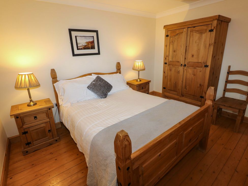 A bedroom with a wooden bed and furniture at The Dairy in Penuel near Llanmorlais