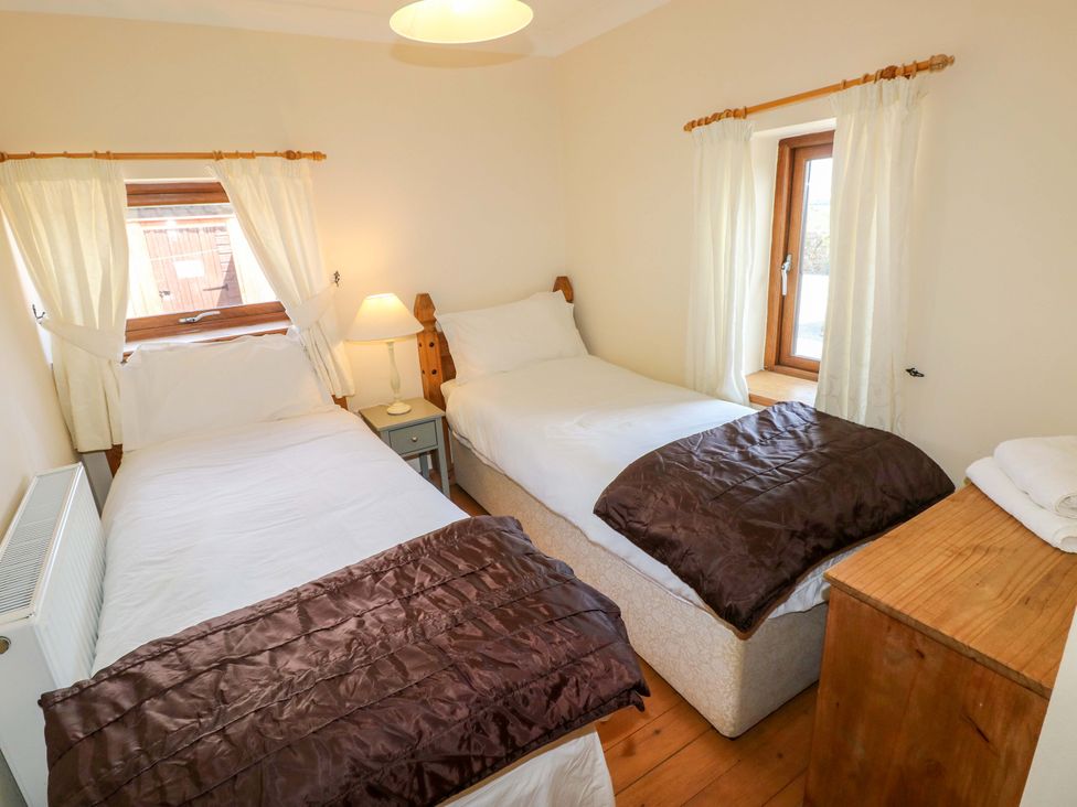 A bedroom with two beds and a window at The Dairy Penuel near Llanmorlais