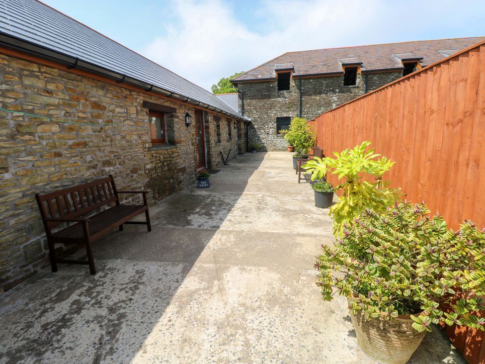 An outdoor pathway with a bench and planters at The Dairy in Penuel near Llanmorlais