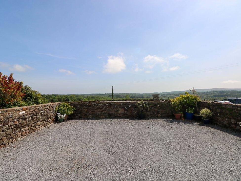 An outdoor area with a stone wall and gravel ground at The Dairy in Penuel near Llanmorlais