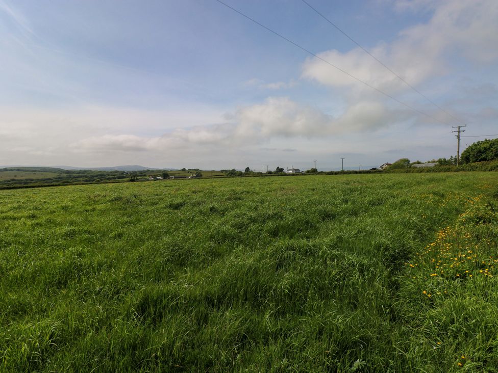 A grassy field under a cloudy sky at The Dairy in Penuel near Llanmorlais