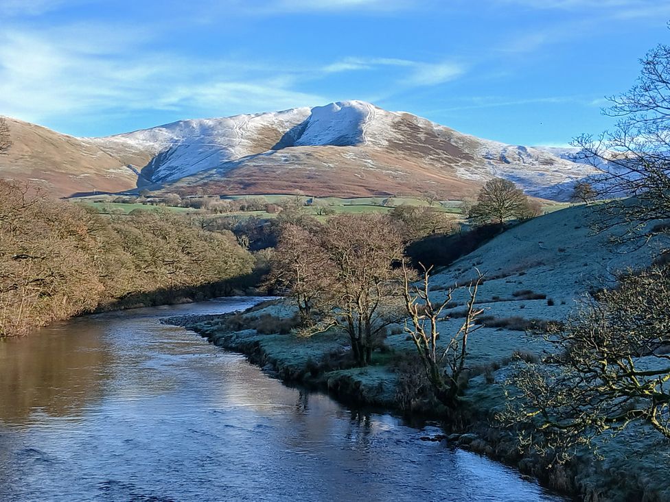 A river with trees and mountains in the background at Riddings Barn Howgill near Sedbergh
