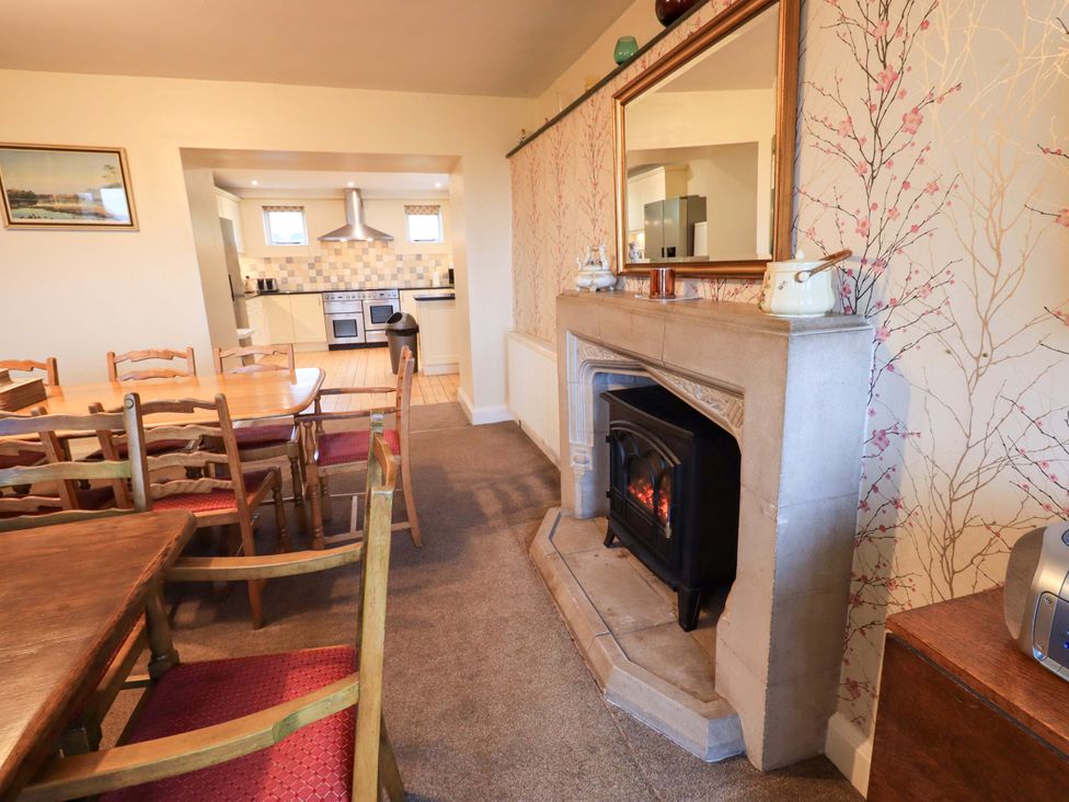 A dining room with a fireplace and dining table at Ghyll Bank House in Staveley near Windermere