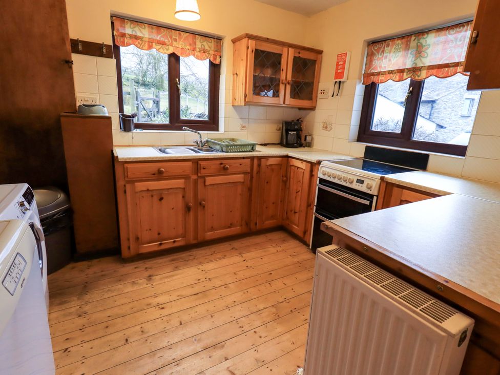 A kitchen with wooden cabinets and appliances at Ghyll Bank House Staveley near Windermere