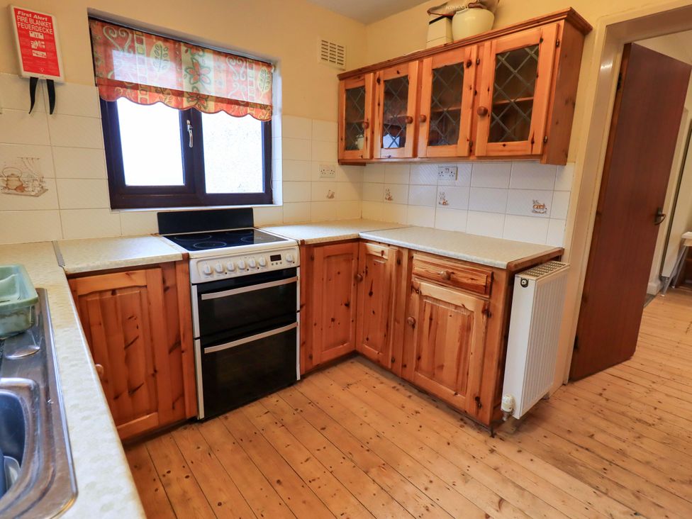 A kitchen with wooden cabinets and stove at Ghyll Bank House in Staveley near Windermere