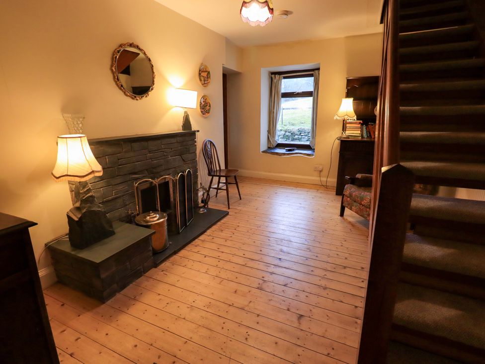A hallway with a fireplace and a wooden chair at Ghyll Bank House in Staveley near Windermere
