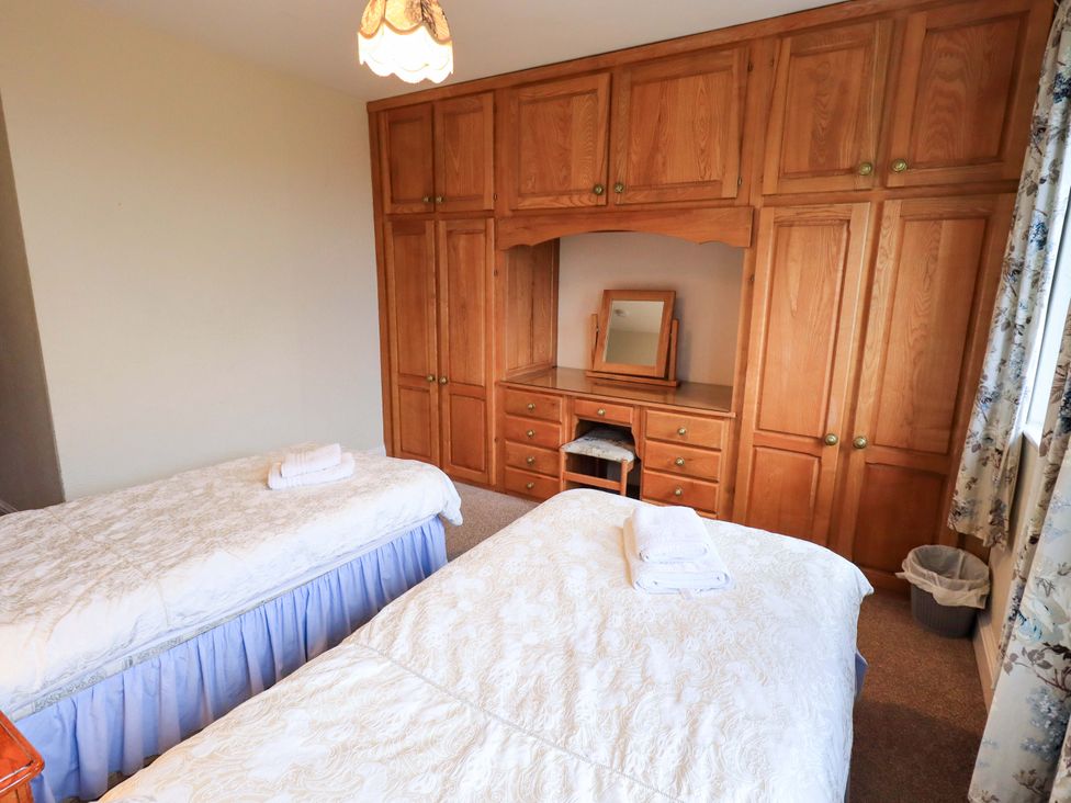 A bedroom with two beds and a wardrobe at Ghyll Bank House in Staveley near Windermere