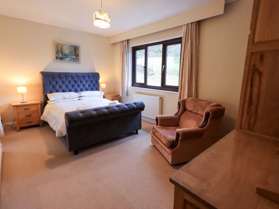 A bedroom with a bed and chair at Ghyll Bank House in Staveley near Windermere