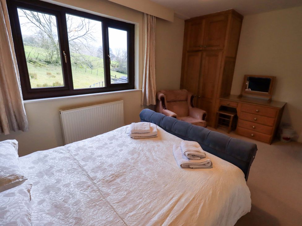 A bedroom with a bed and armchair at Ghyll Bank House in Staveley near Windermere