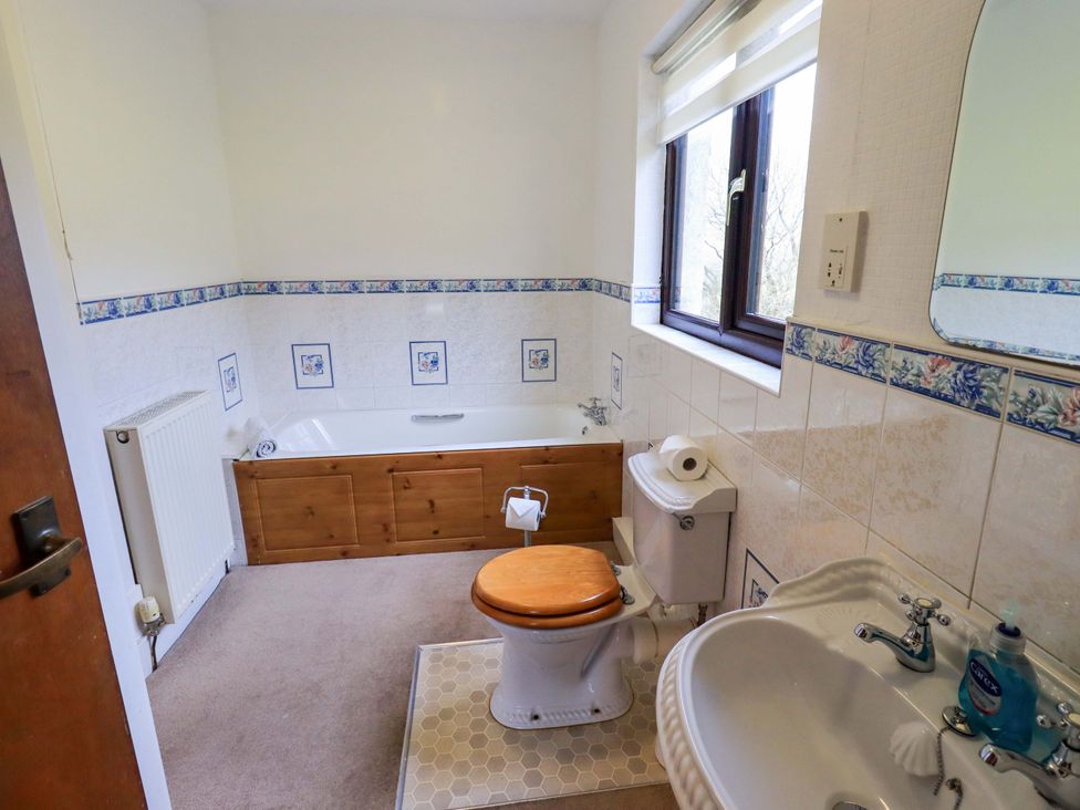 A bathroom with a bathtub, toilet, and sink at Ghyll Bank House Staveley near Windermere