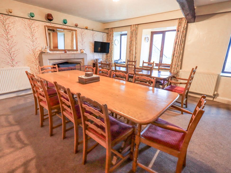 A dining room with a long table and chairs at Ghyll Bank House Staveley near Windermere