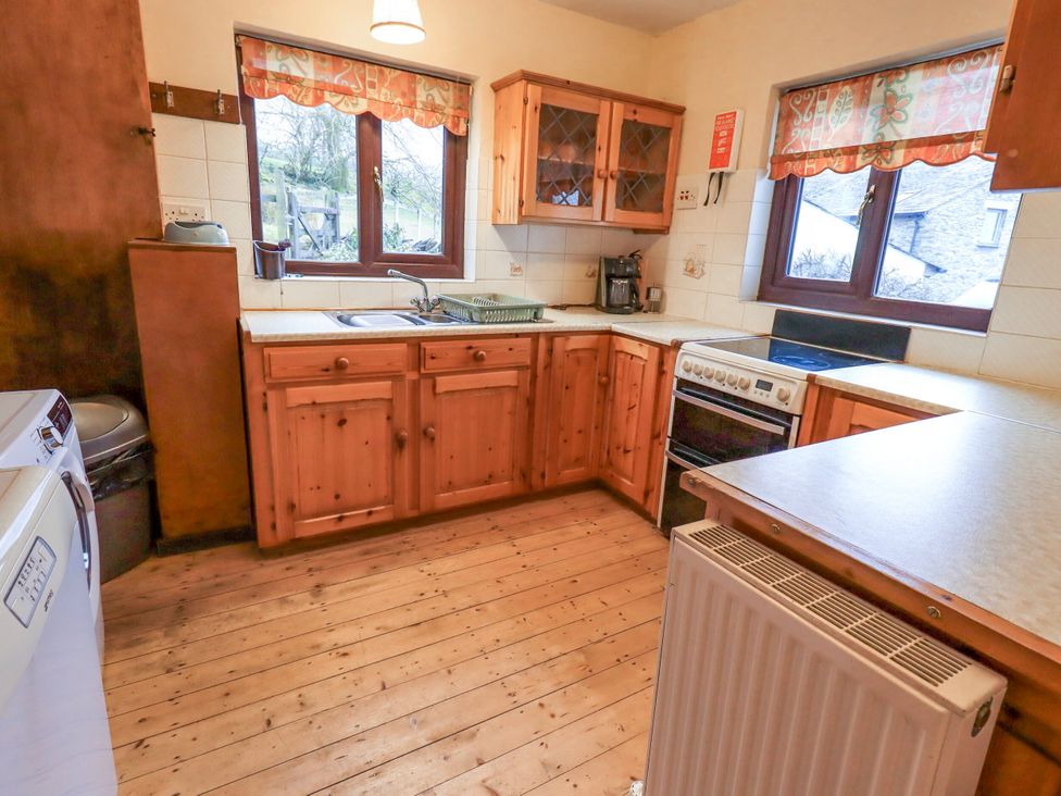 A kitchen with wooden cabinets and a sink at Ghyll Bank House Staveley near Windermere