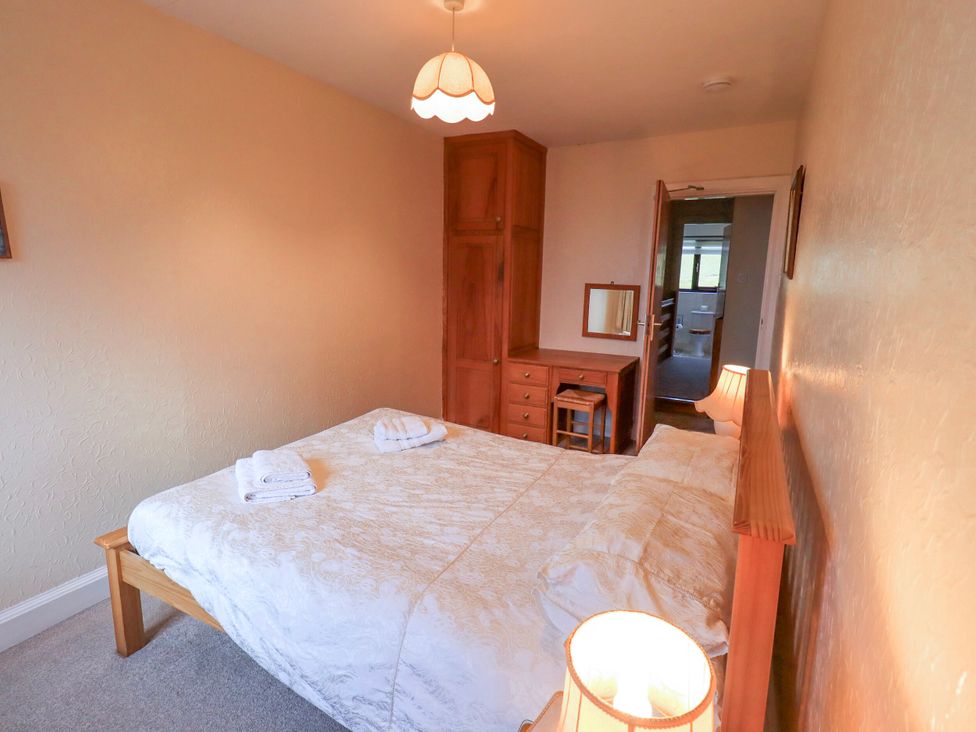 A bedroom with a bed and wooden furniture at Ghyll Bank House in Staveley near Windermere
