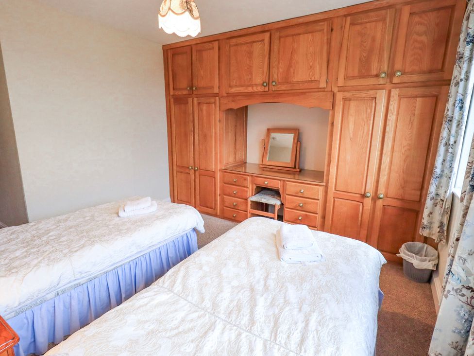 A bedroom with two beds and a wardrobe at Ghyll Bank House in Staveley near Windermere