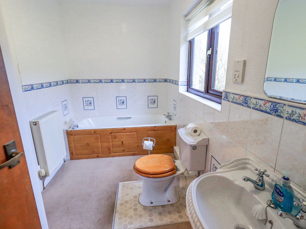 A bathroom with a bathtub, toilet, and sink at Ghyll Bank House Staveley near Windermere
