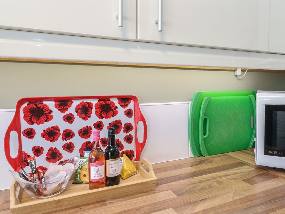 A kitchen countertop featuring trays, bottles, and cutting boards at Steam Cottage in Aviemore