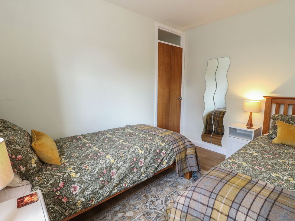 A bedroom with two beds and a nightstand at Steam Cottage in Aviemore