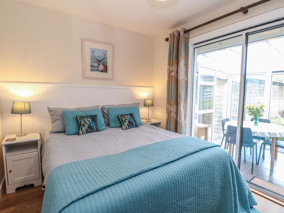 A bedroom with a bed and sliding doors to a dining area at Steam Cottage in Aviemore