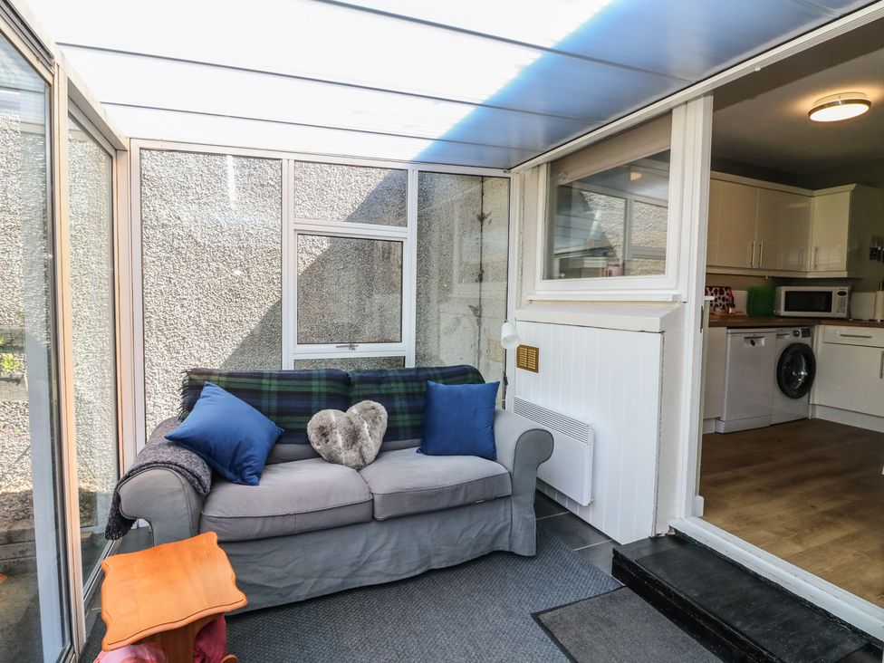 A conservatory with a sofa and side table at Steam Cottage in Aviemore