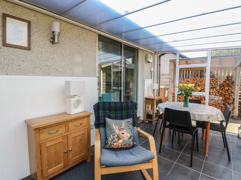 A conservatory with a table and chairs at Steam Cottage in Aviemore