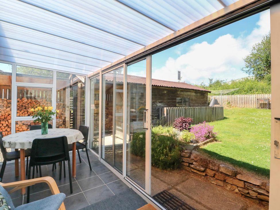 A conservatory with a table and chairs overlooking the garden at Steam Cottage in Aviemore