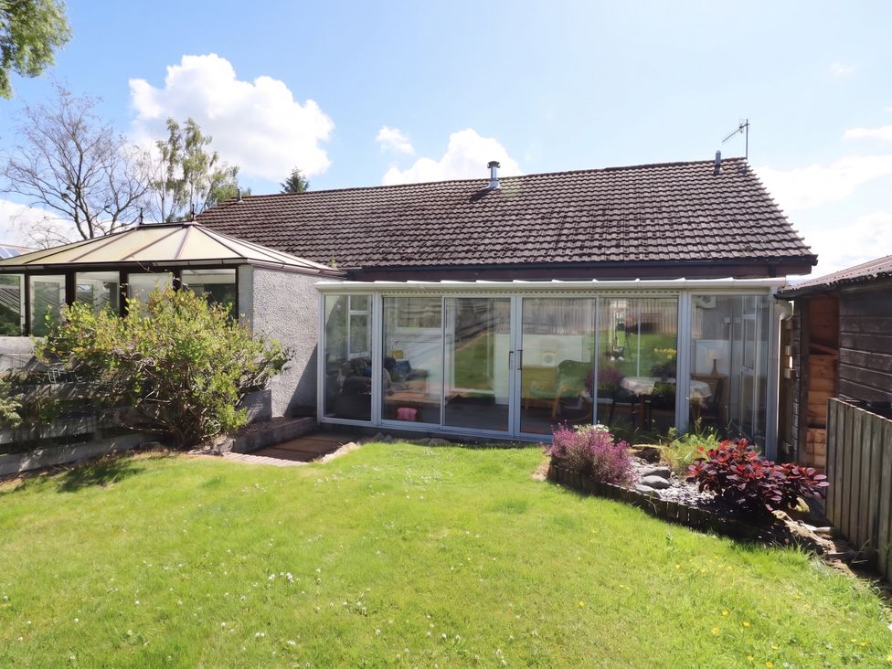 A house with a glass extension and garden at Steam Cottage in Aviemore