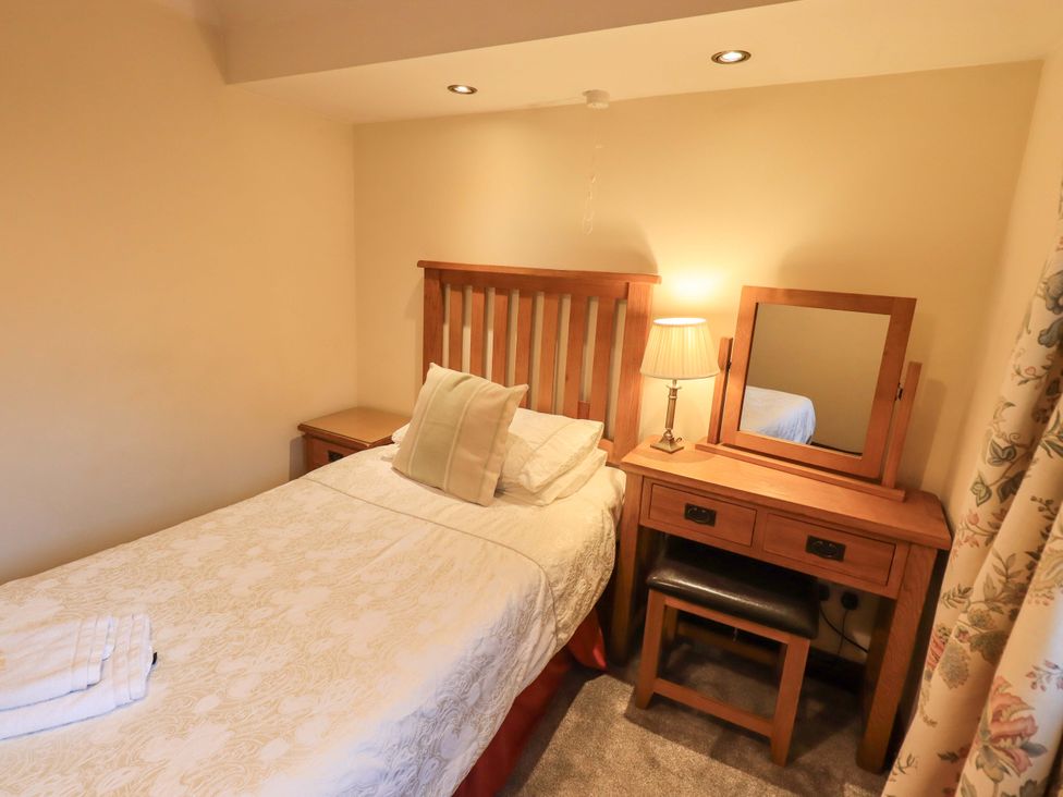 A bedroom with a bed, bedside table, and dresser at Ghyll Bank Bungalow Staveley near Windermere