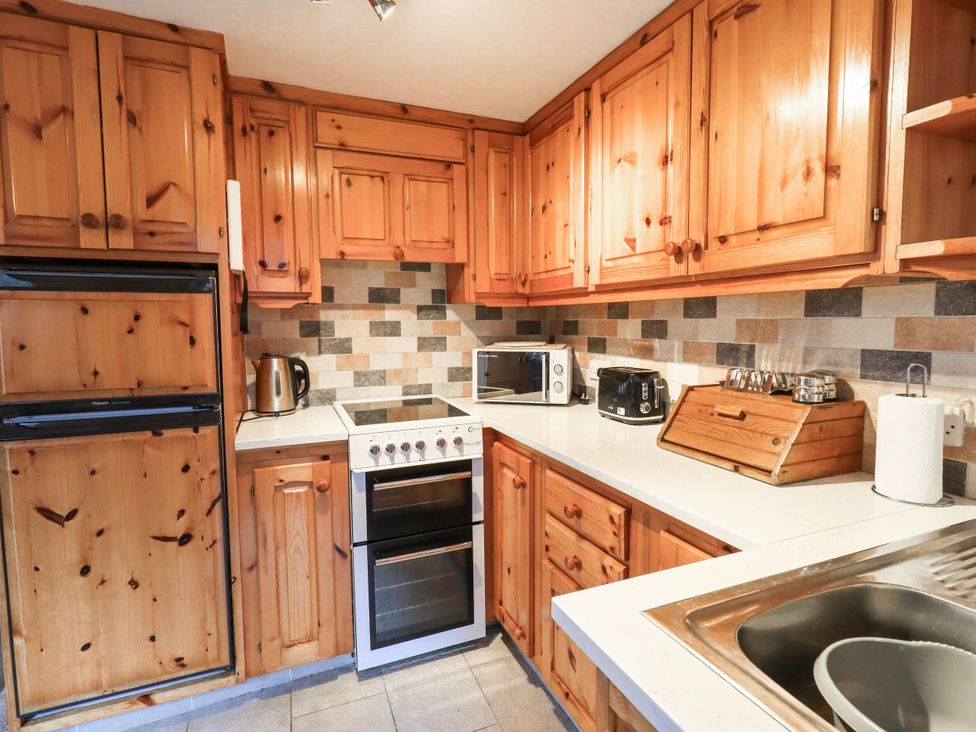 A kitchen with wooden cabinets and appliances at Ghyll Bank Bungalow Staveley near Windermere