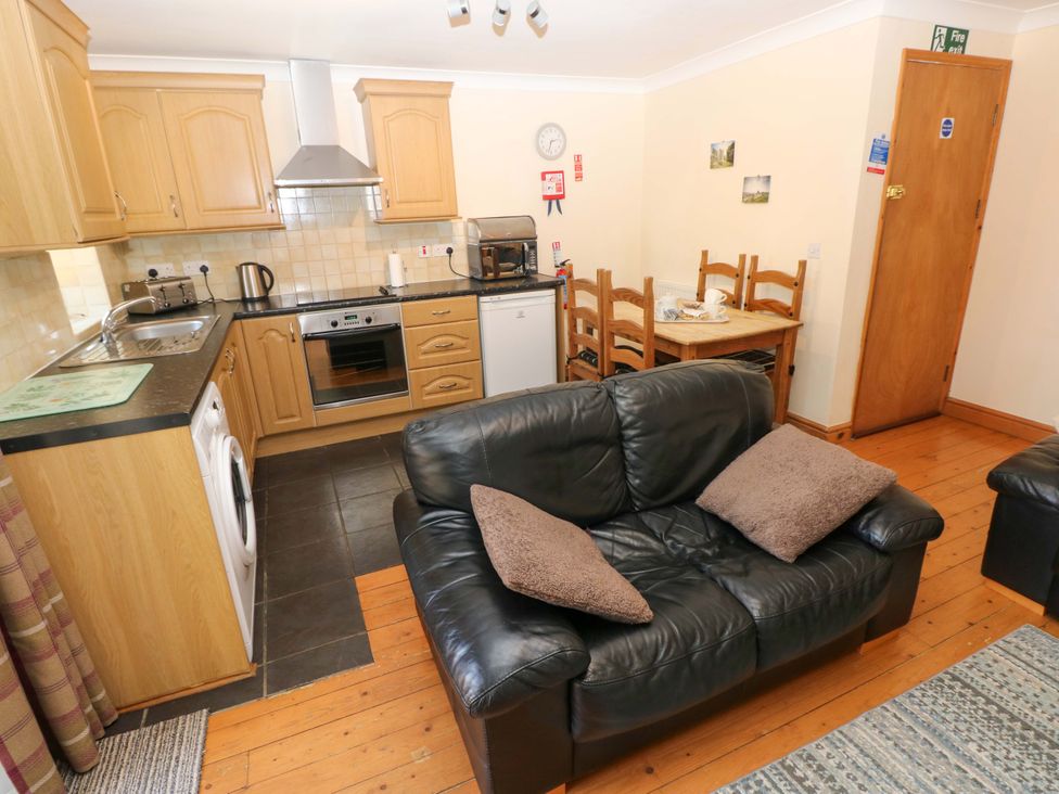 A kitchen with a sofa and dining table at The Stall in Penuel near Llanmorlais