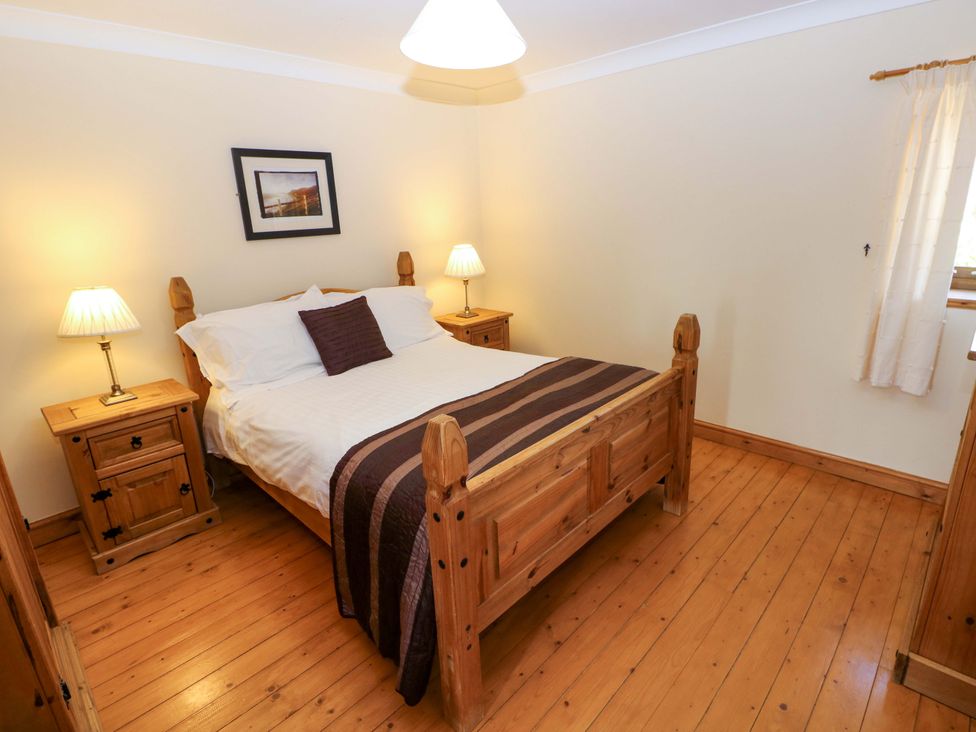 A bedroom with a bed and nightstands at The Stall in Penuel near Llanmorlais