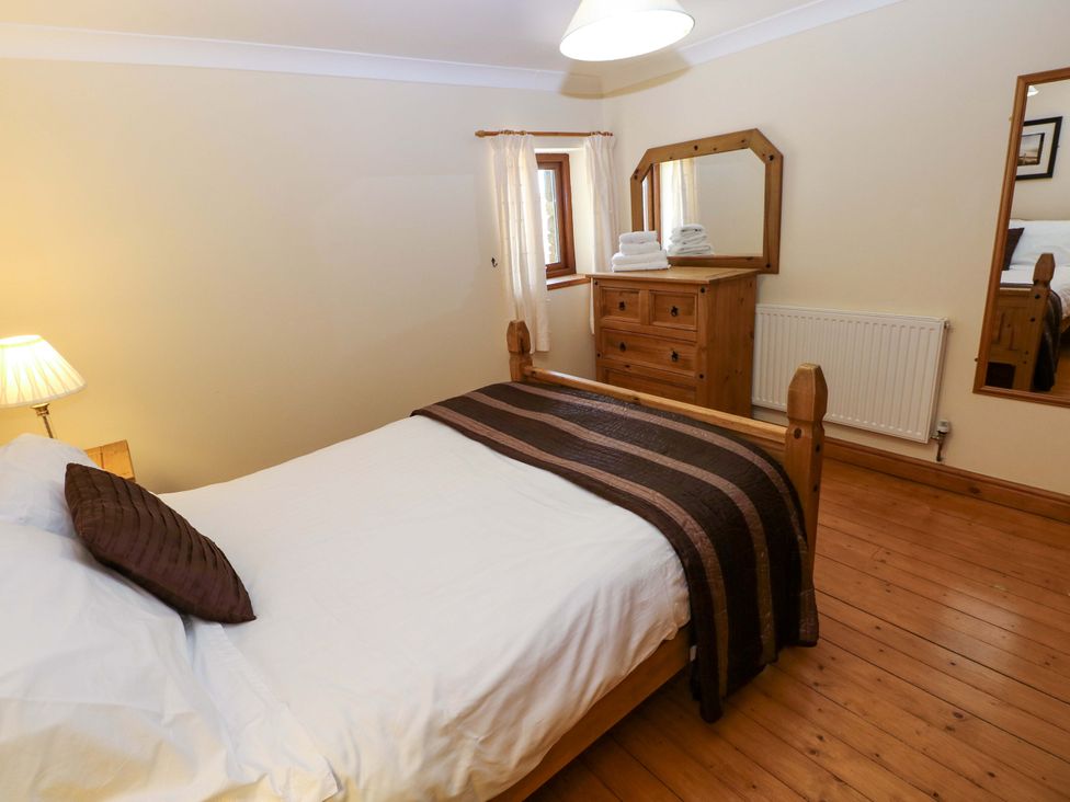 A bedroom with a bed, dresser and window at The Stall in Penuel near Llanmorlais