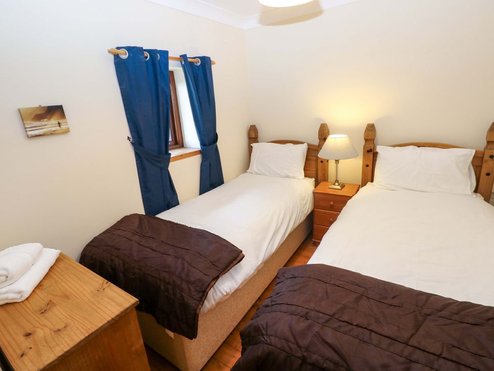 A bedroom with two single beds and a bedside table at The Stall in Penuel near Llanmorlais
