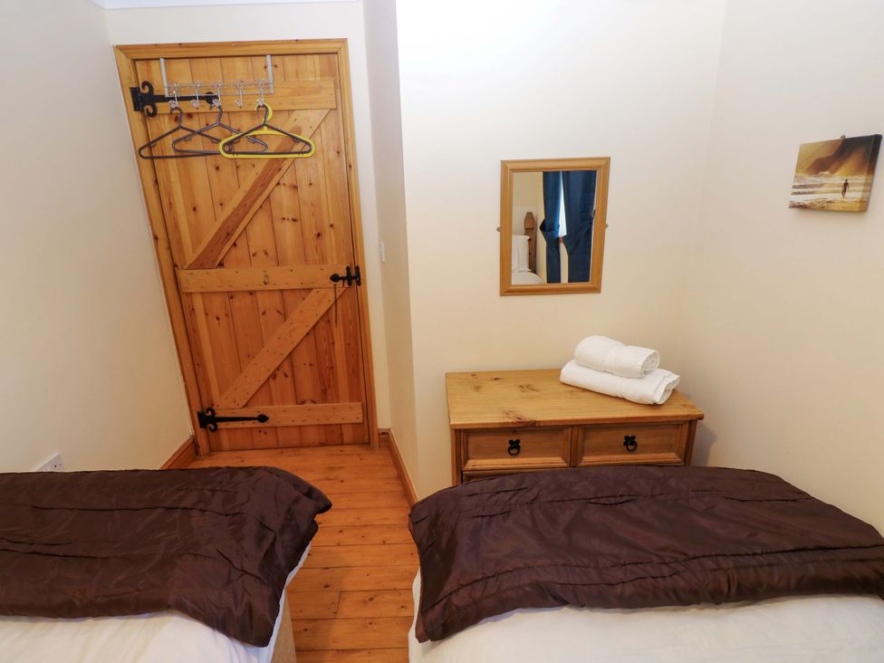 A bedroom with two beds and a wooden door at The Stall in Penuel near Llanmorlais