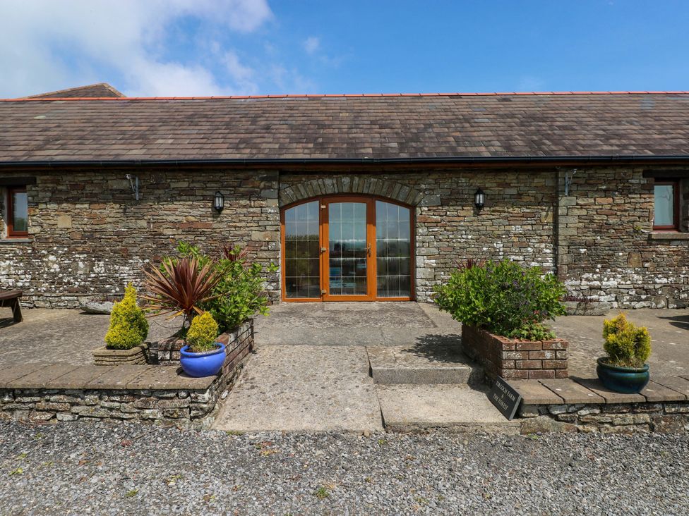 An outdoor entrance area with stone wall and planters at The Stall in Penuel near Llanmorlais
