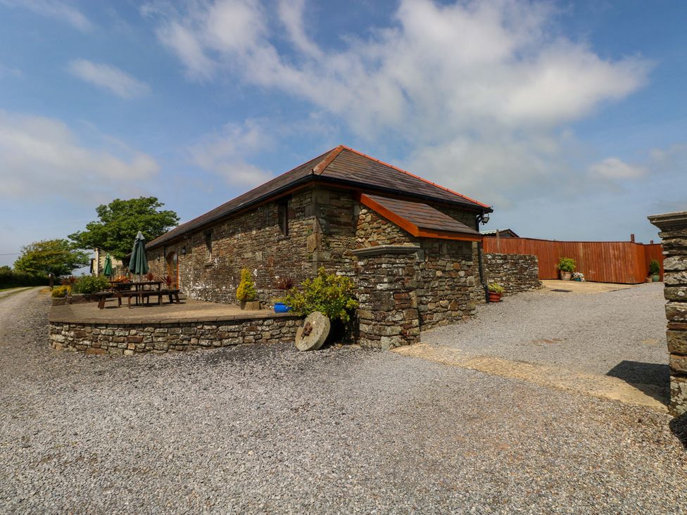 A stone building with outdoor tables and umbrellas at The Stall in Penuel near Llanmorlais